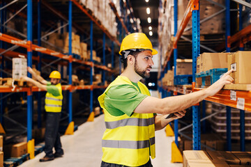 A focused warehouse worker looking at boxes for shipment.