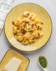 Mac and cheese with bacon, parmesan piece and spoon of parsley