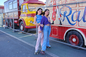 Friends in vintage clothes wearing classic skates next to a circus parade