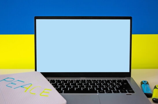Flag of Ukraine on the background and wide digital screen of laptop for text or message. War with Russia. Cyber attack, sanctions, economic collapse. Message for world peace
