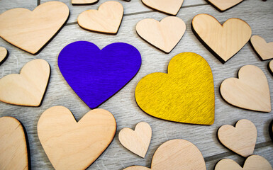 Lots of wooden hearts on the wooden table and two hearts in colors of Ukrainian flag