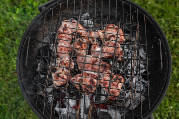 Top view of seasoned pork on the grill. Grilling shashlik outside on a barbecue grill. Outdoor grill party in the summer season. Sunny summer evening.