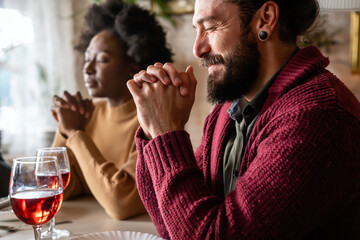 Young multiethnic couple praying to Lord to bless their food and day