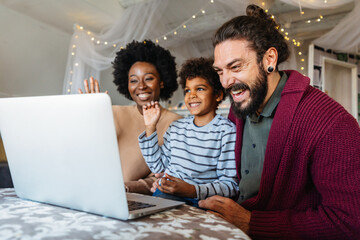 Young multiethnic cheerful family talking through video chat with relatives