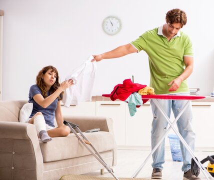 The husband helping leg injured wife in housework