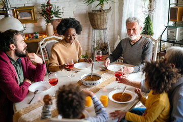 Happy multiethnic multigeneration family having fun together around kitchen table.