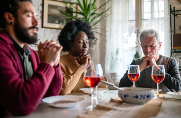 Family and religious concept. Group of multiethnic people with food praying before meal