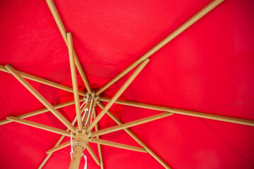 Under red summer parasol with vintage style antique wooden frame.