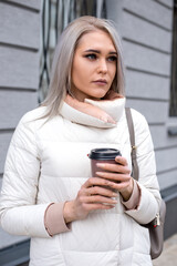 Vertical blond thoughtful woman, waiting for friends company, coffee break after working day, cold weather. Close up