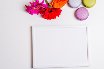 colorful flowers and macarons above white frame