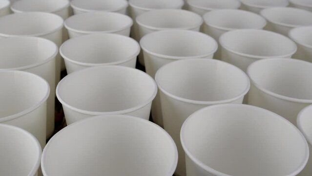 Row of white disposable paper cup for coffee or hot beverage on dark backdrop rotate slowly.