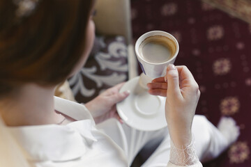 Coffee in the hands of the bride on the morning of the wedding day