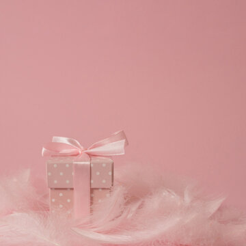 Romantic Easter or Valentine's Day composition on pastel pink background, with feater clouds and polka dot present or gift - minimal arrangement