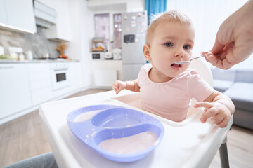 Charming tiny girl in pink clothes at the morning breakfast at home