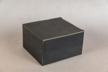 Rectangular black box on a gray background. Closed cardboard package with correct geometric shape.