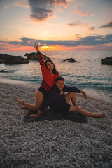 couple lovers at the beach enjoying time together and sunset above the sea