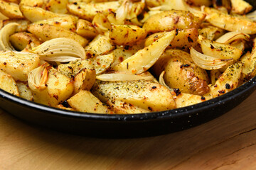 roasted potatoes in a frying pan, cooked food, delicious crust, one object on a wooden background