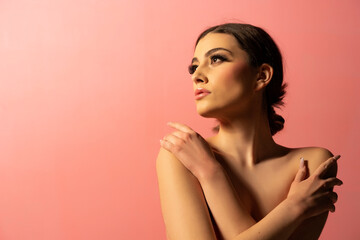 A beautiful natural girl with smooth skin and make-up on a pink background.
