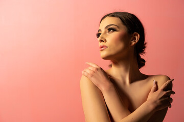 Fototapeta premium A beautiful natural girl with smooth skin and make-up on a pink background.