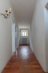 Front view of a corridor inside an ancient villa. Terracotta floor and white walls.