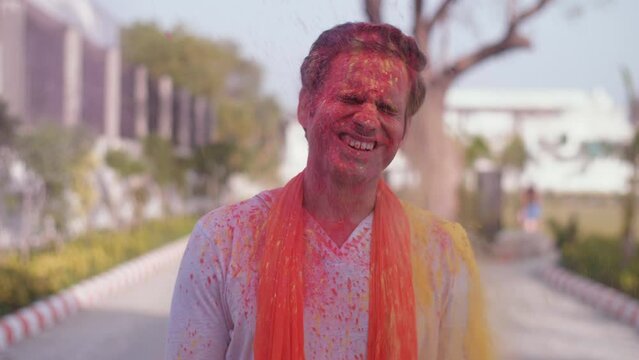 Organic color splash on man's face on Holi - Holi festival  safe Holi  Dry Holi. Splashes of Gulal colors being thrown on the face of a cheerful young man during the Indian festival of colors - a H...