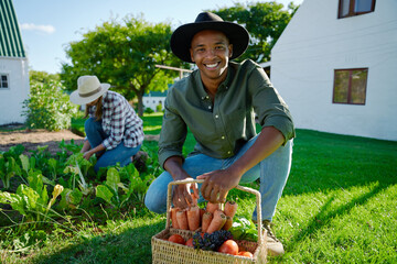 Mixed race male farmer working in vegetable garden picking fresh produce with female colleague