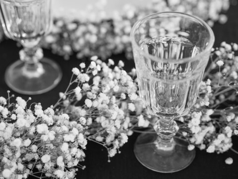 Black and white picture of a table setting with black table cloth and white flower garland