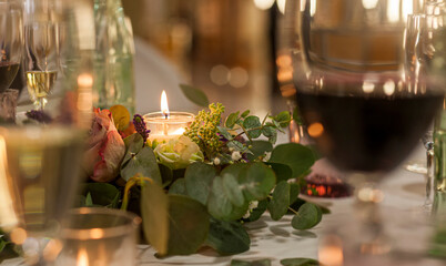 decoration with a lighted candle between wine glasses