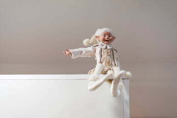little elf dressed in white sitting in the corner of the doorway