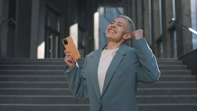 Woman gesturing happily while getting good news on mobile