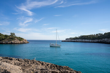 Voilier au milieu d'une crique à la mer turquoise avec mouette et nageur.