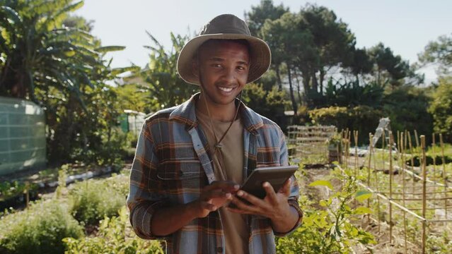 Mixed race male farmer typing on digital tablet while standing outdoors