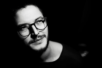 Black and white portrait of young man on dark background. Close-up view.