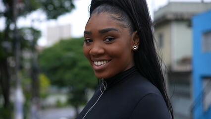 A Brazilian girl turning head to camera smiling while walking in street