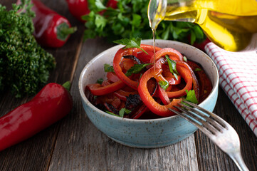 Pouring olive oil over a red bell pepper salad