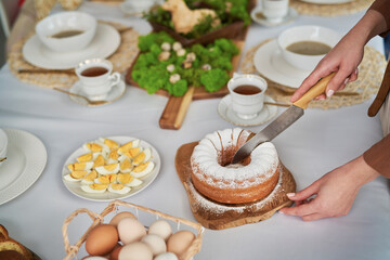 Unrecognizable woman cutting easter cake on the table