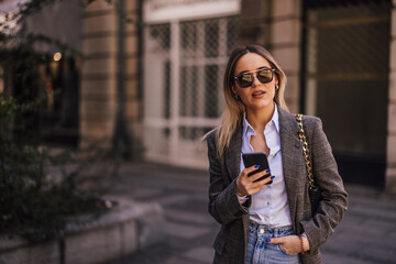 Obraz premium Portrait of a blonde girl with sunglasses on, having a purse, an