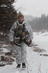 Fototapeta premium Soldier in winter camouflaged uniform in Modern warfare army on a snow day on forest battlefield with a rifle. Model face very similar to Ukraine prime minister.