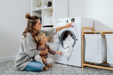 Woman spends time with young child in laundry room, bathroom, performs household duties while on...