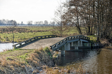 Obraz premium pedestrian bridge made of concrete, steel and wood as part of a hiking trail on a sunny day in early spring in Krimpenerwaard region in the Netherlands