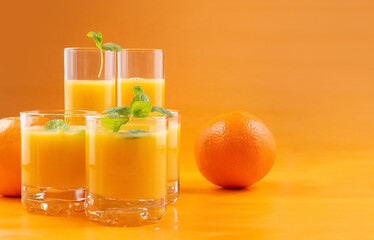 Orange juice in glasses and fresh oranges on an orange background. Concept. Photo