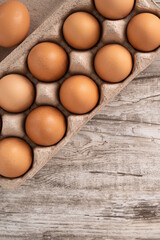 Fresh brown chicken eggs in a kraft paper egg carton.