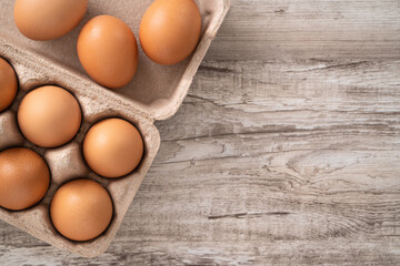 Fresh brown chicken eggs in a kraft paper egg carton.
