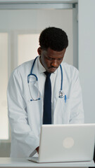 General practitioner looking at modern laptop to work on medical treatment and healthcare system. Physician using device to find checkup information to cure patient with disease.