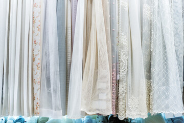Assortment of tulle curtains in a shop. Large selection of accessories for windows made of lightweight mesh material. selective focus