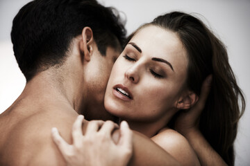 Absorbed in passion. Studio shot of a young couple sharing an intimate moment against a gray...
