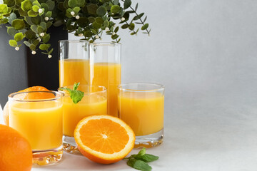 Orange juice in glasses and fresh oranges on a gray background. Concept. Photo