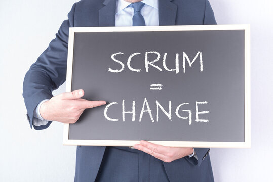Projektleiter oder SCRUM Master mit einer Tafel auf der SCRUM = CHANGE steht. Konzept agiles Projektmanagement und sich stetig änderne Anforderungen an Projekte und Teams