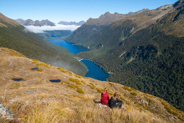 Hiking couple admiring scenic view of lakes Fergus, Lake Gunn and Livingstone mountain range,...