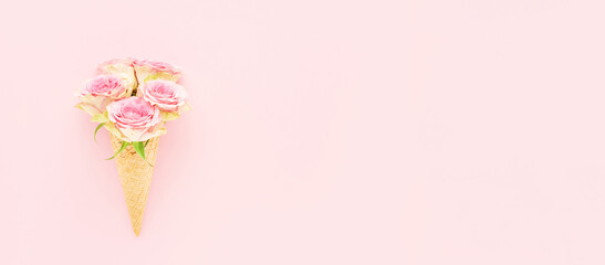 Pink roses in a waffle ice cream cone on a pink background. Mothers Day, Valentines Day, bachelorette, summer concept. Banner